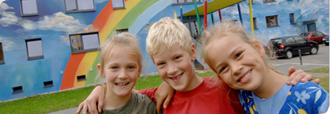 Hier sehen Sie Kinder, die vor einer Schule stehen.